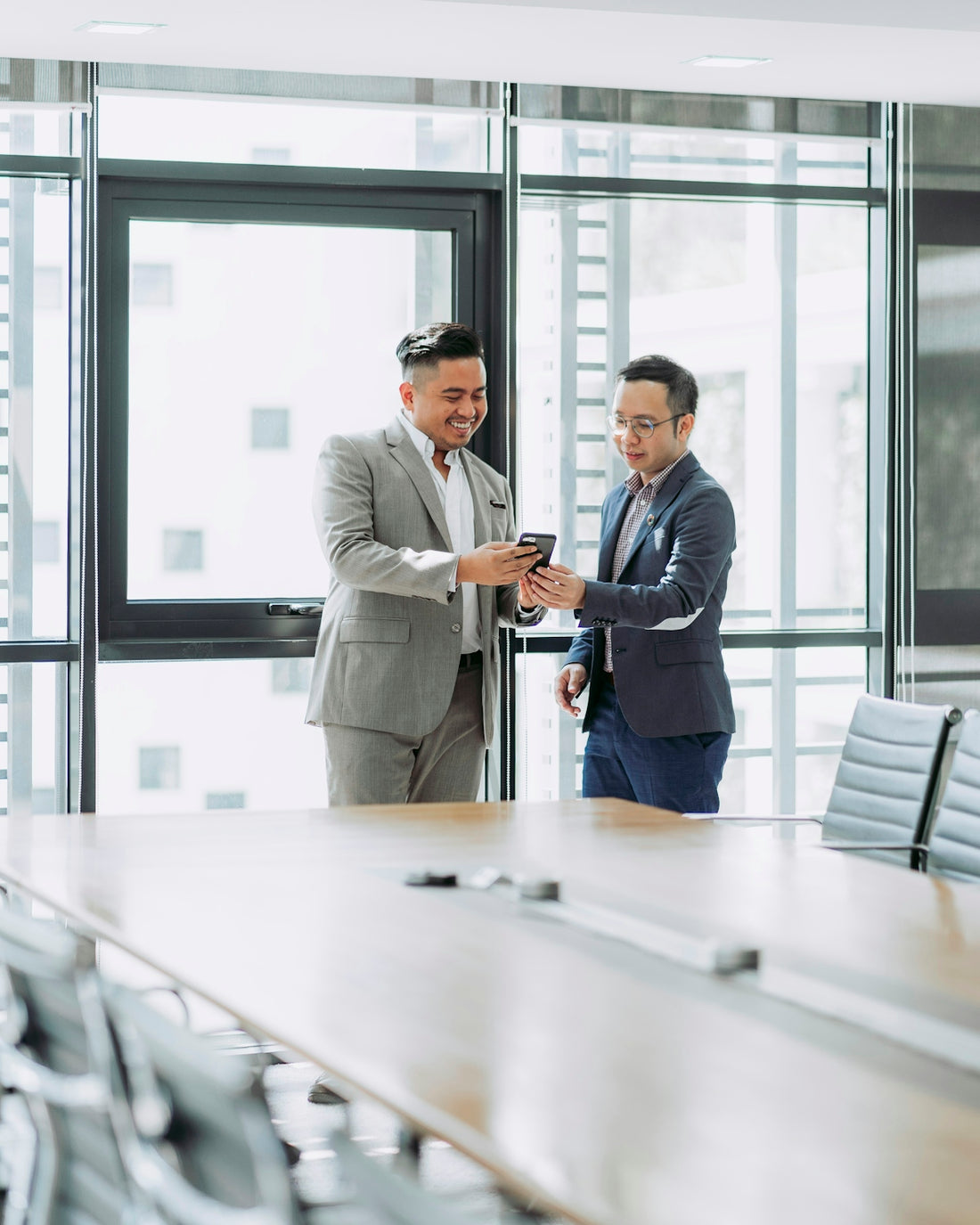 two businessmen looking at phone in office